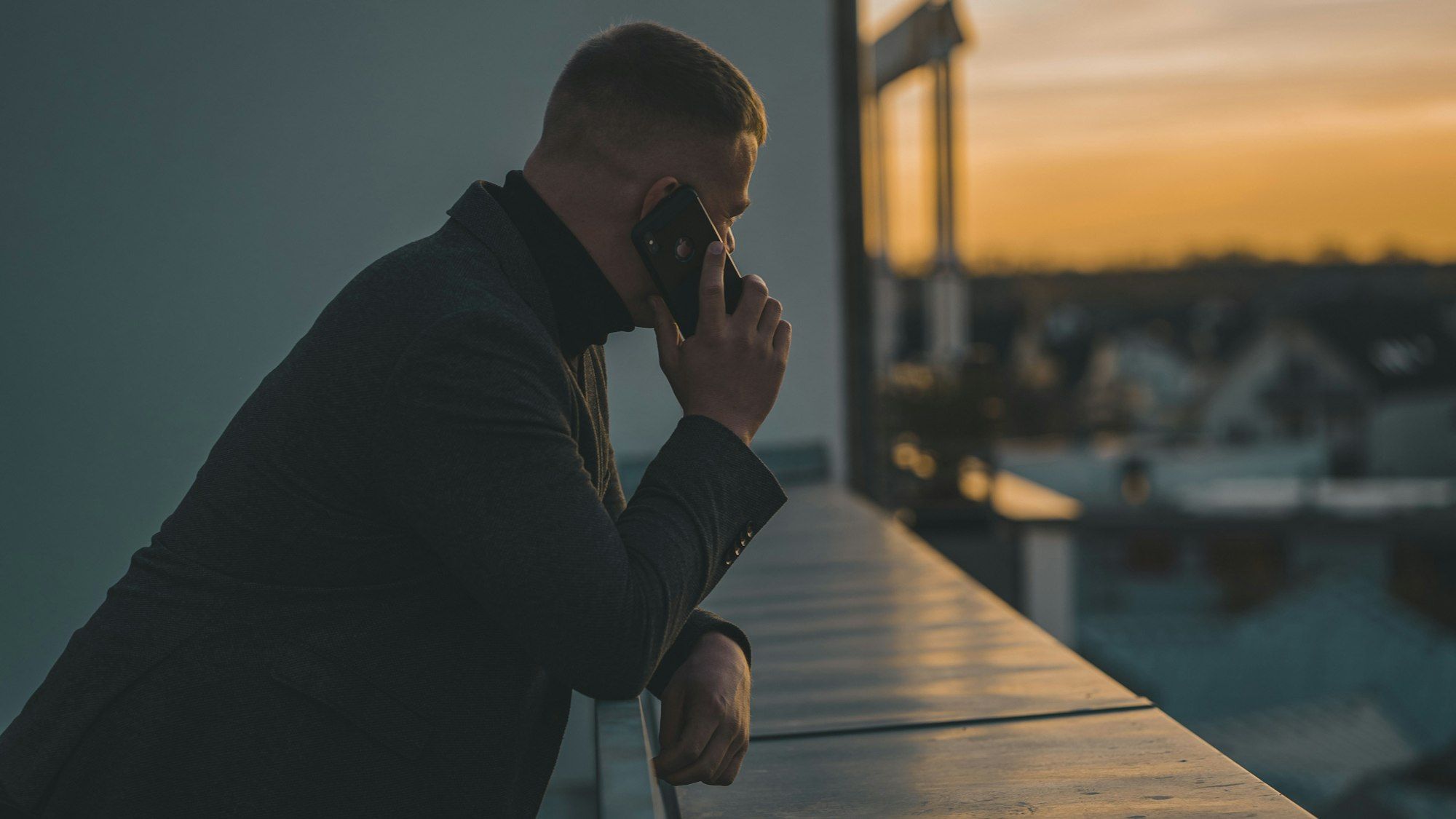 Business owner on a balcony at dusk, on the phone talking through funding after a relationship separation