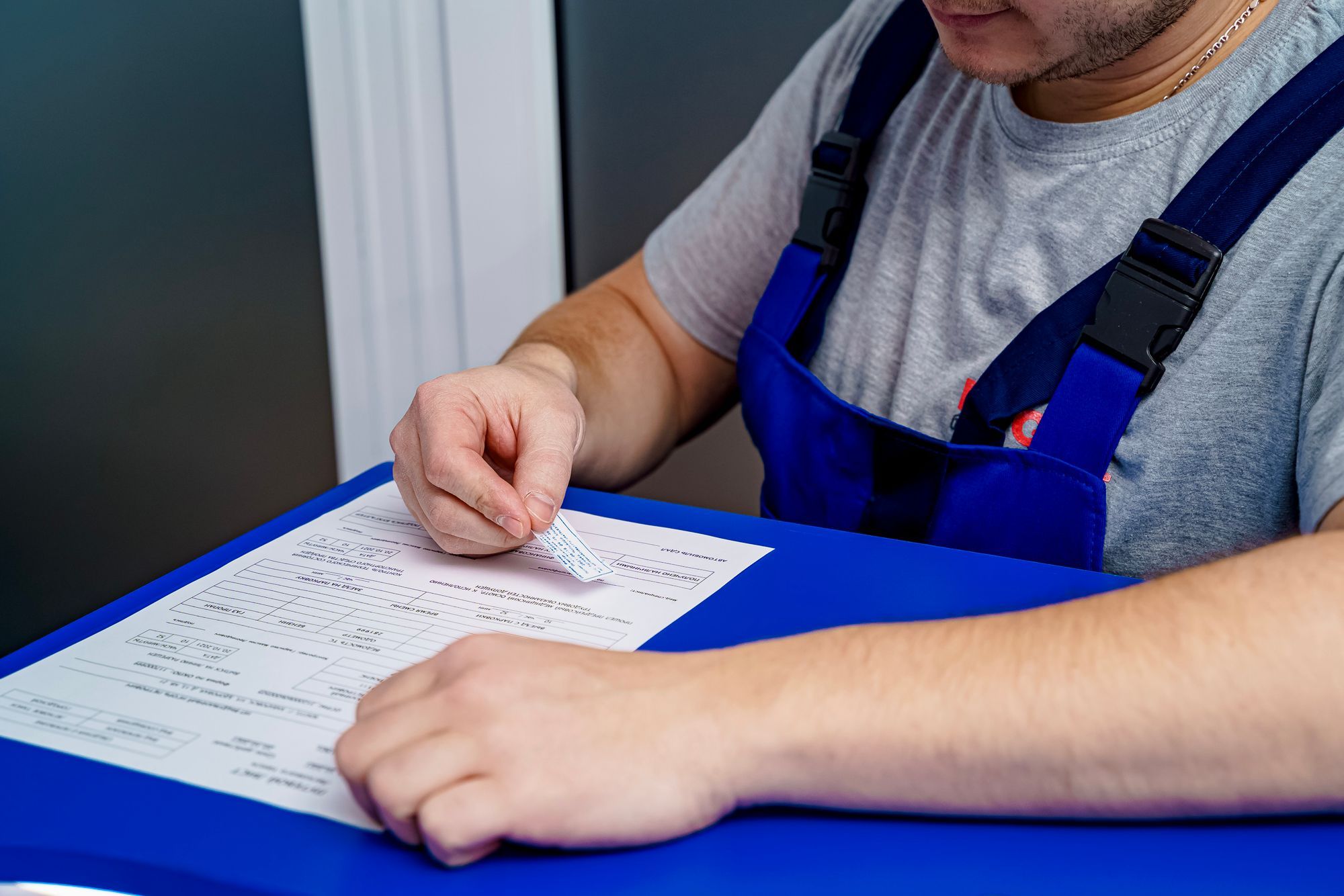 Tradesperson in work overalls going through a printed form at a desk, the paperwork that follows when a customer goes into liquidation owing money