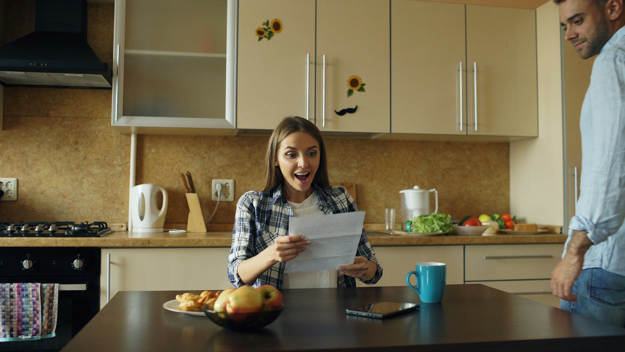 Couple at the kitchen table smiling with relief as they read a letter together