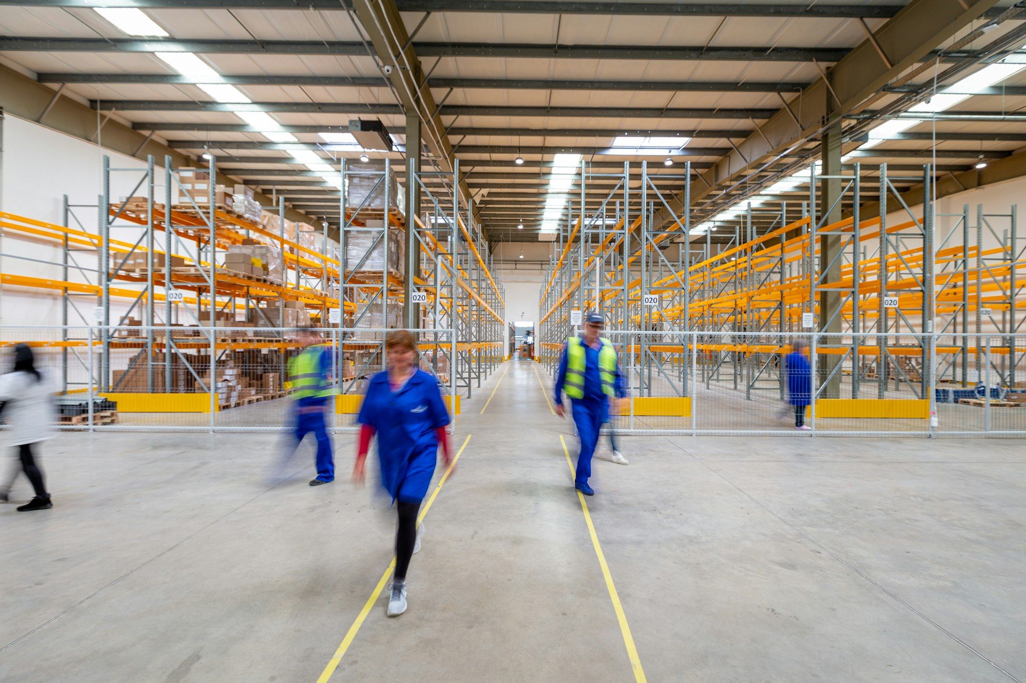 Staff walking through a busy warehouse aisle stacked with stock