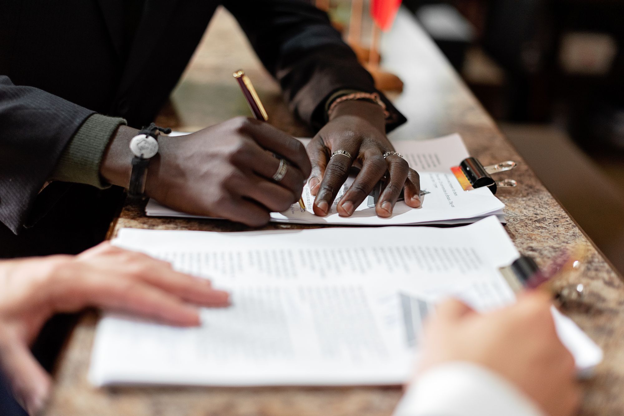 Business owner signing a sale and purchase agreement at a shop counter while the buyer reads through their copy of the contract
